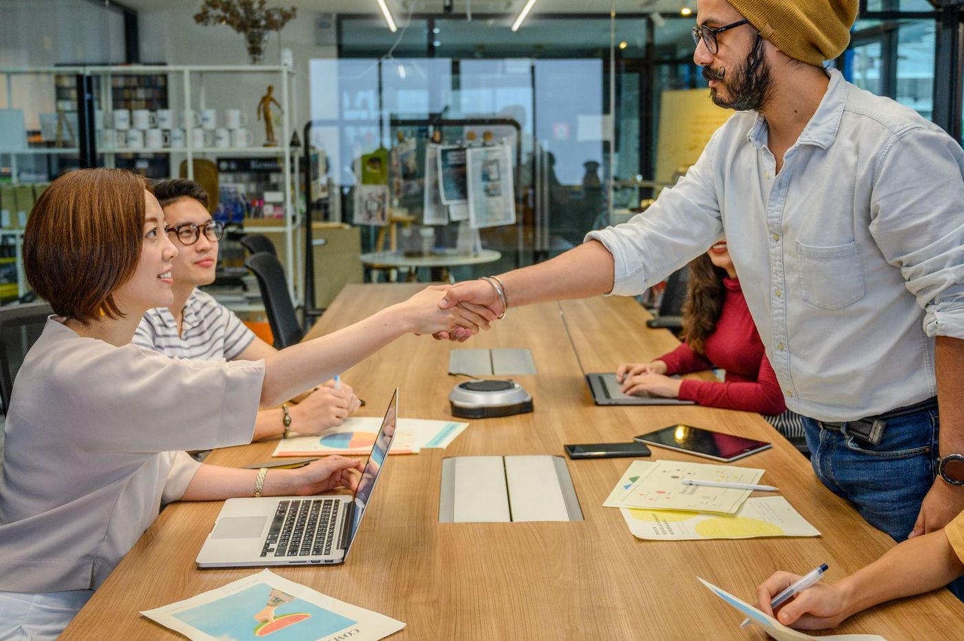 Colleagues shaking hands across a meeting table